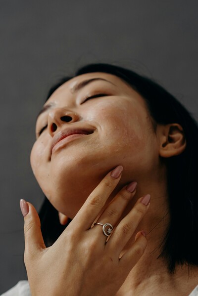 A smiling woman touching her neck and enjoying her firmer, younger skin