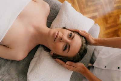 A woman with healthy, glowing skin receiving cosmetic facial acupuncture