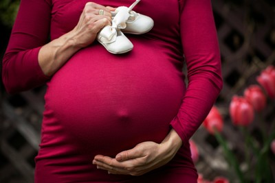 A pregnant woman showing off baby shoes